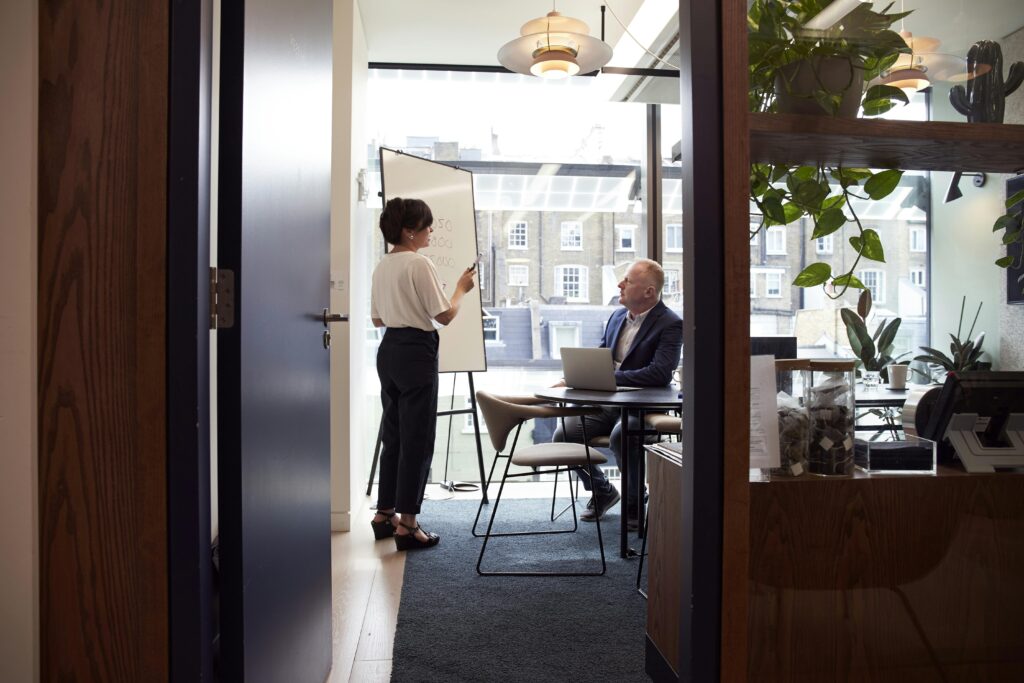 A woman giving a presentation on a whiteboard in an office