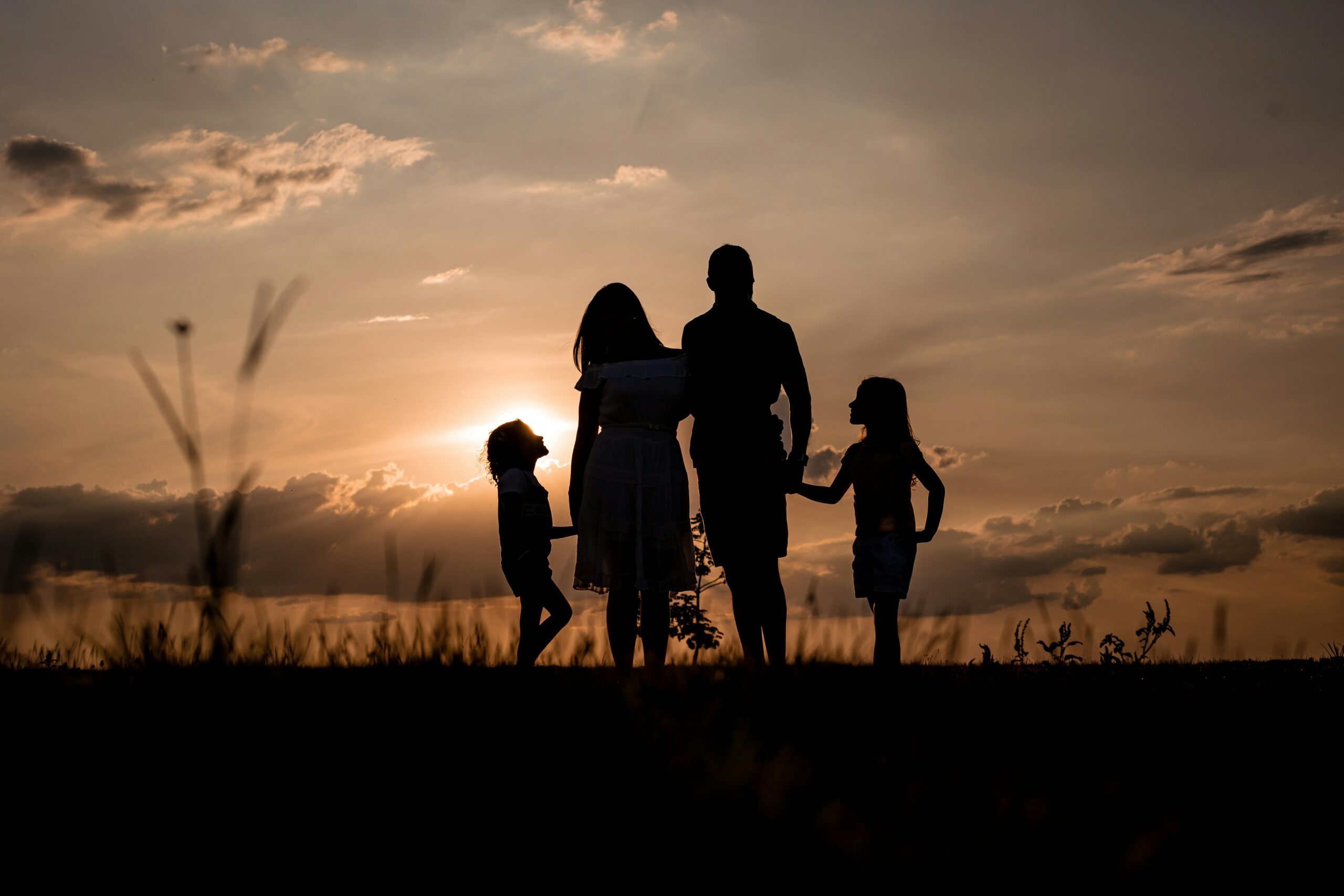 A family stands together in a field at sunset, symbolizing unity, legacy, and generational planning—key themes when considering revocable and irrevocable trusts to protect family wealth.