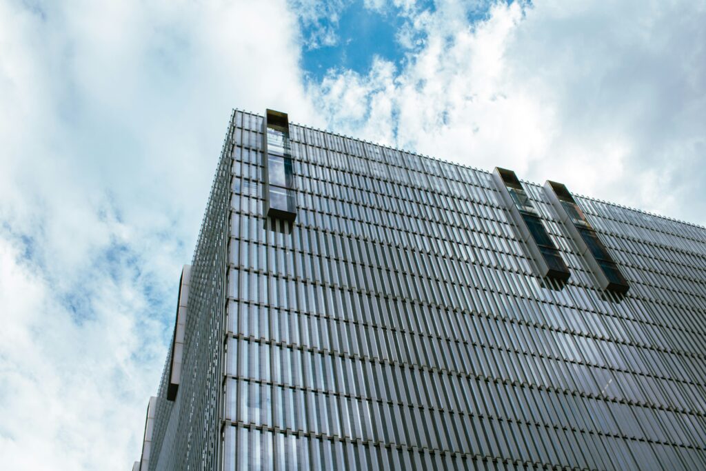 A tall commercial building viewed from below, representing a prime real estate property for sale. The clear sky and sleek architecture highlight its value in the urban property market.