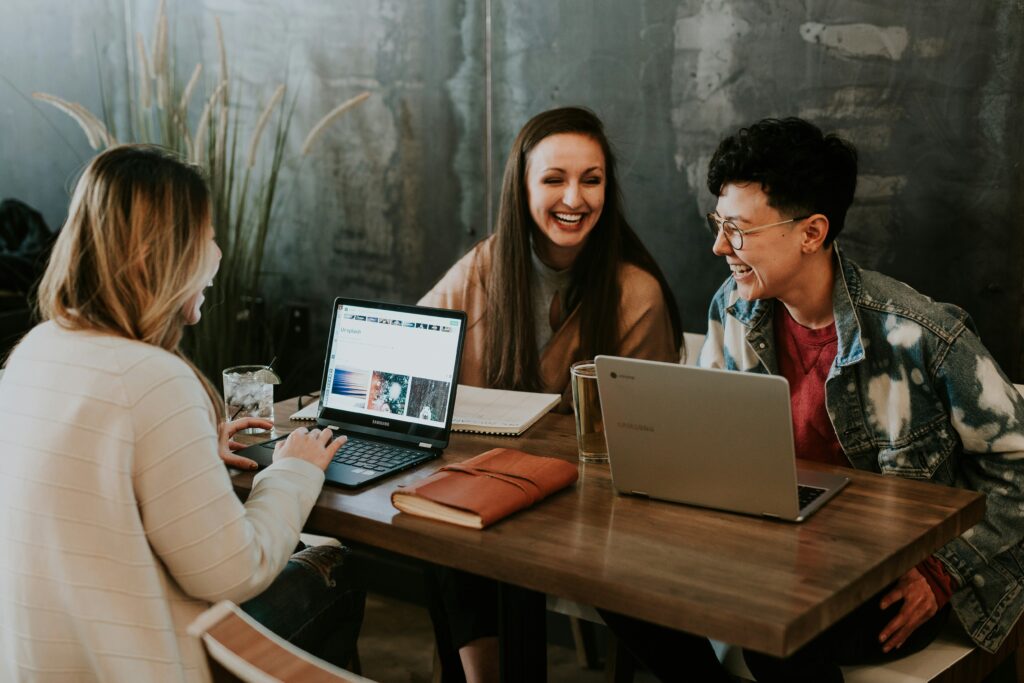 Three professionals laugh and collaborate around a table, reflecting the value of strong client relationships and clear communication when navigating the complexities of multi-state tax planning.