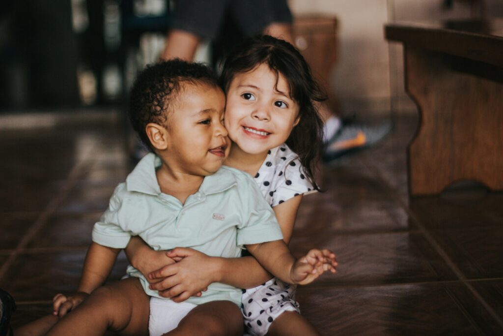 A young girl hugs a younger boy in a warm, candid moment, symbolizing the importance of family and dependents—key considerations when filling out a W-4 form to claim eligible tax benefits.