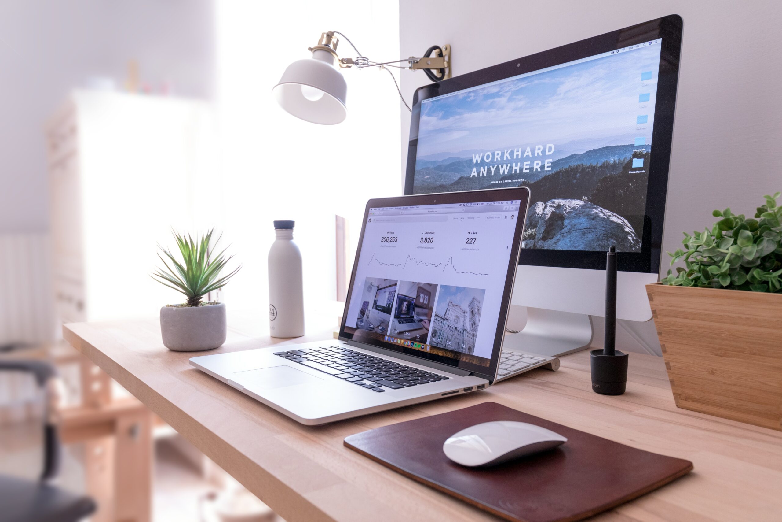 A workspace featuring a MacBook Pro on a table next to a white iMac and a Magic Mouse, symbolizing efficient management of multiple 1099s.