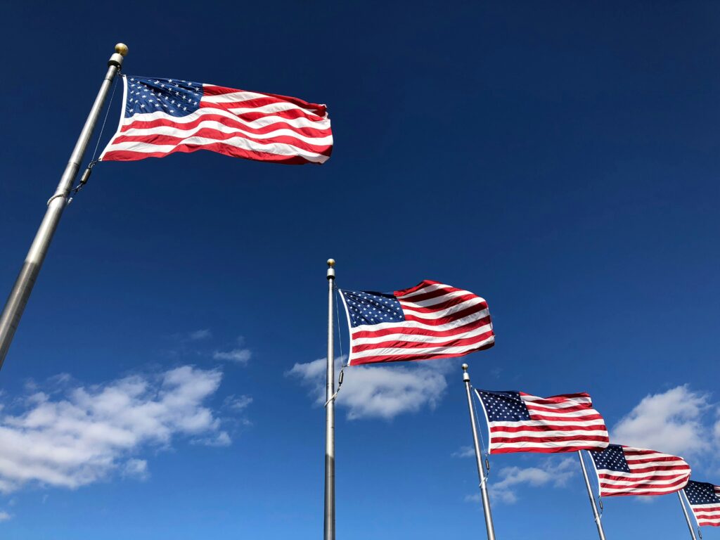 A row of U.S. American flags waving under a clear sky, symbolizing the diverse and complex landscape of multistate tax issues that businesses face across different jurisdictions.