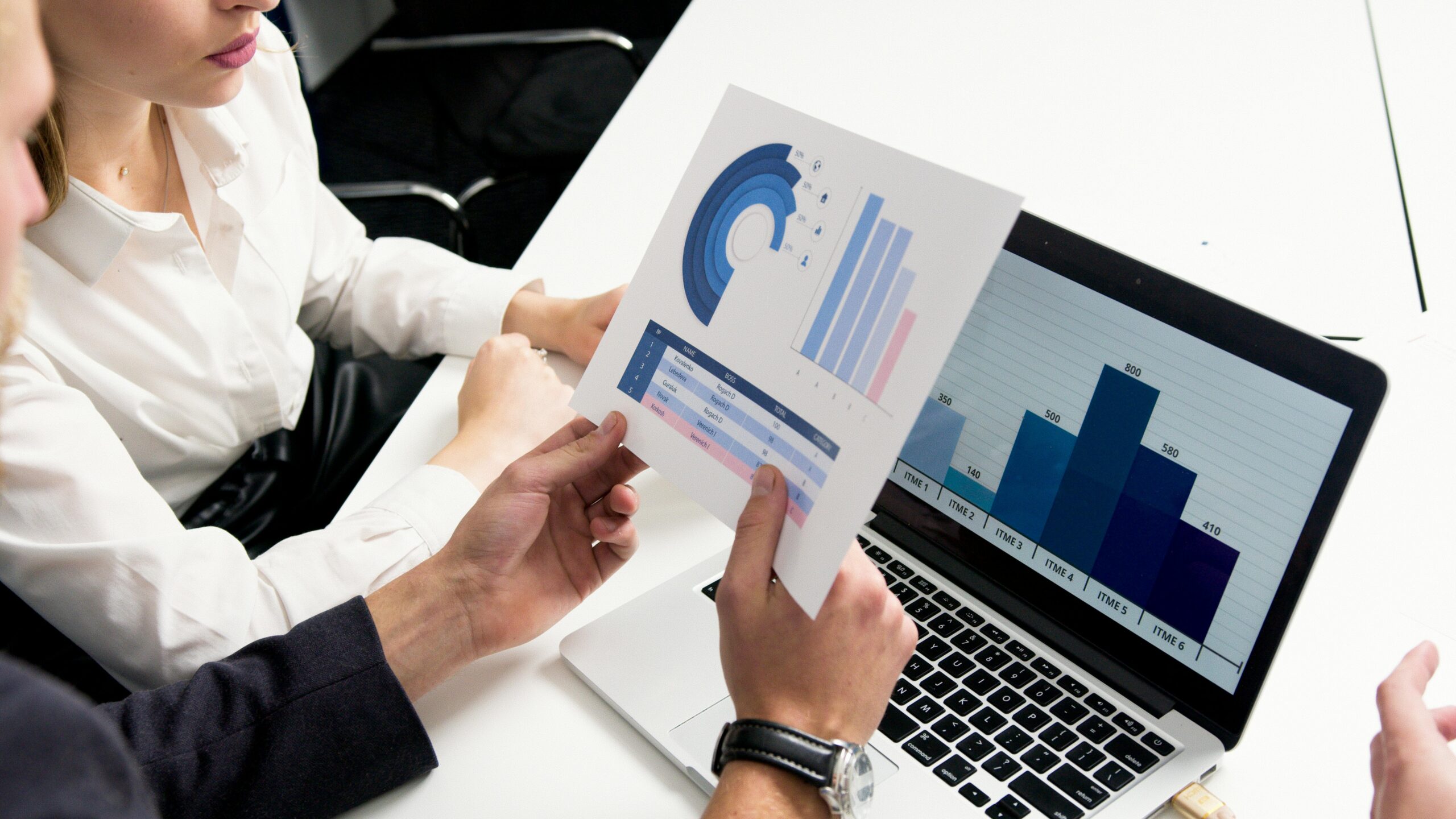 An image of two people holding a document over a computer.