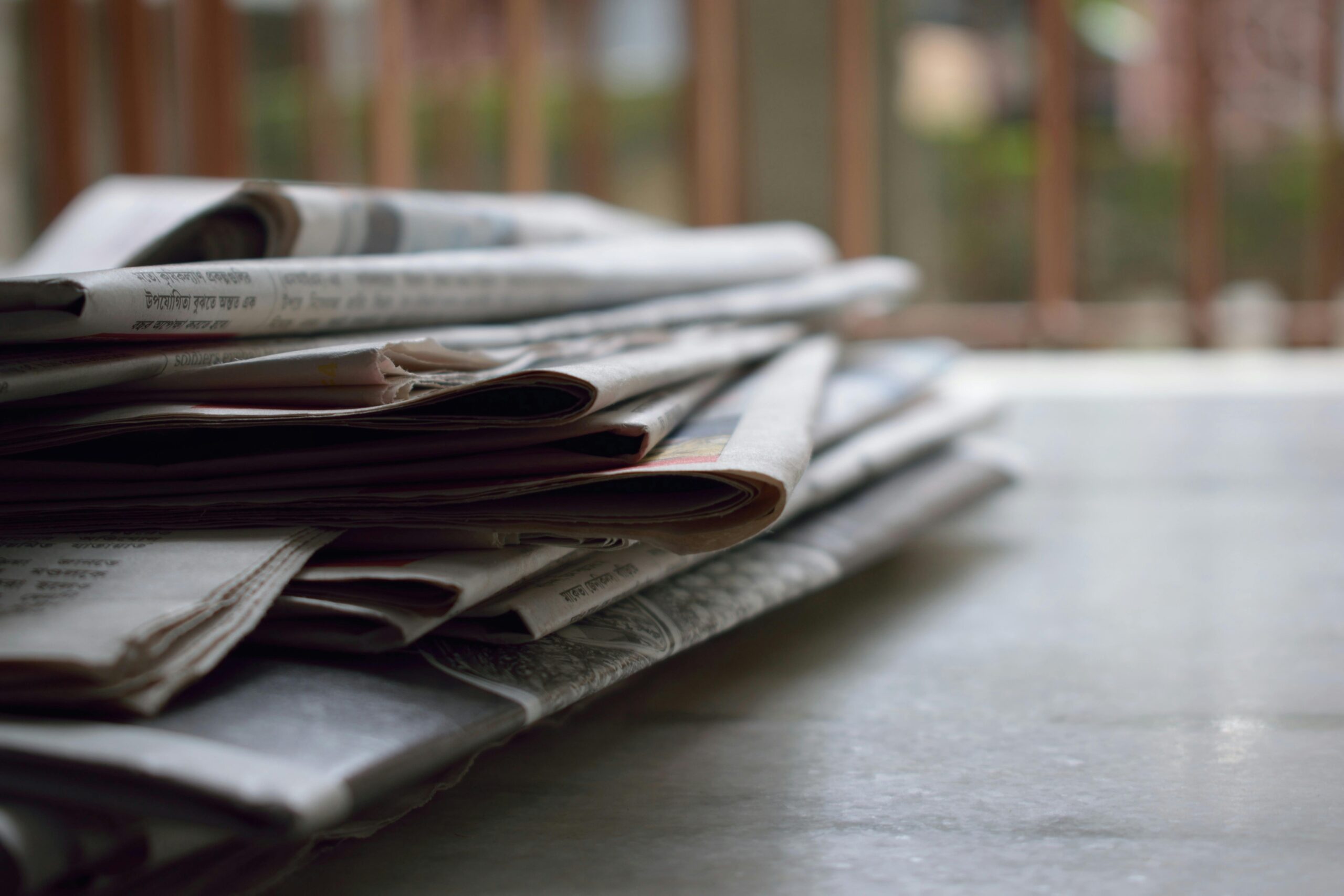 A stack of tax and finance magazines sits on a wooden surface, symbolizing the rapid flow of policy updates covered in the July 30, 2025 Tax Advisor Weekly. Topics include Trump’s India tariff deadline, IRS staffing cuts, casino reporting threshold changes, and new retiree deductions under the OB3 Act.