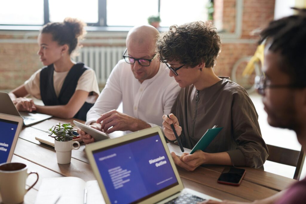 A team collaborates around a laptop during a meeting—representing the strategic shift toward automation and digital tools in today’s modern tax firms.