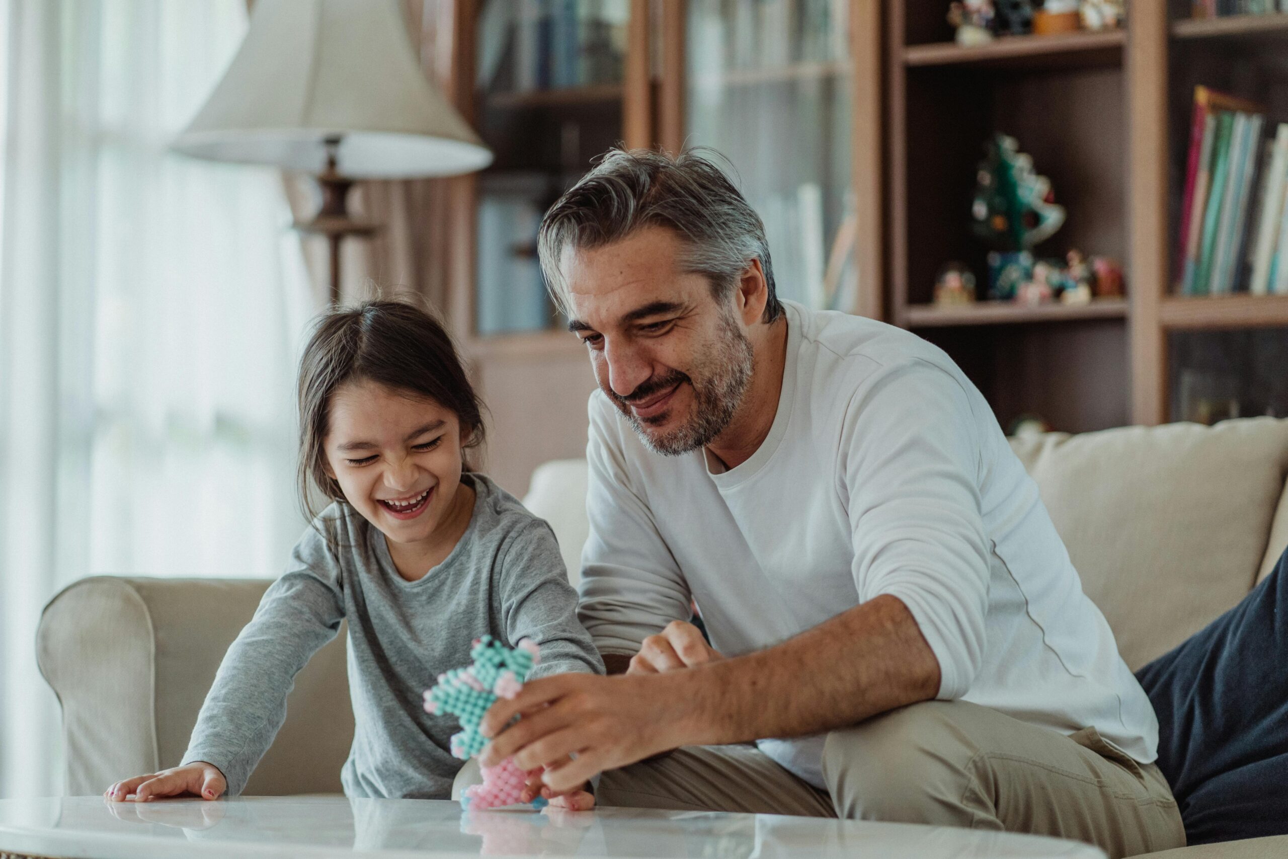 Father and daughter are sitting on the couch together. The One, Big, Beautiful Bill (OBBB), like other major life events, is a key time to review your financial planning as this legislation offers major, time-sensitive benefits for high-net-worth individuals to preserve wealth and reduce tax burden.