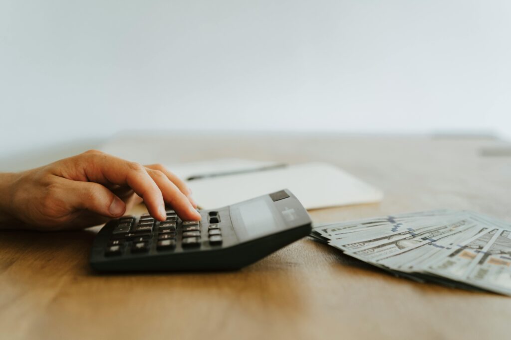 An image a close up of someone using the calculator on a table.