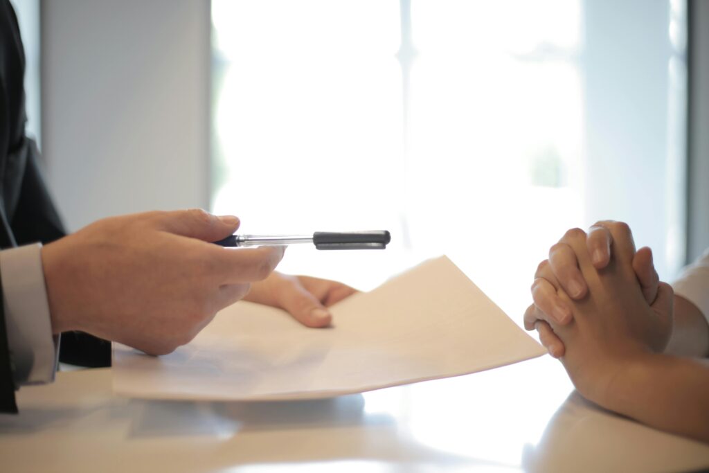 Person handing over a pen with paper.