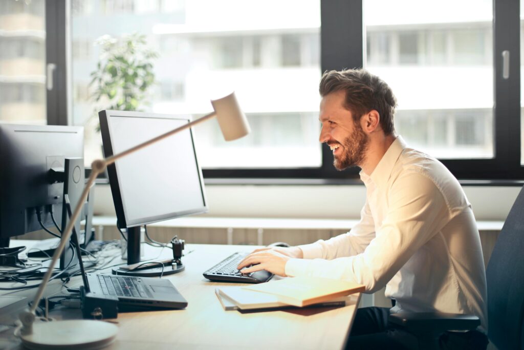 A smiling professional at a computer—representing how tax advisors can simplify document workflows and improve client satisfaction with a secure client portal.
