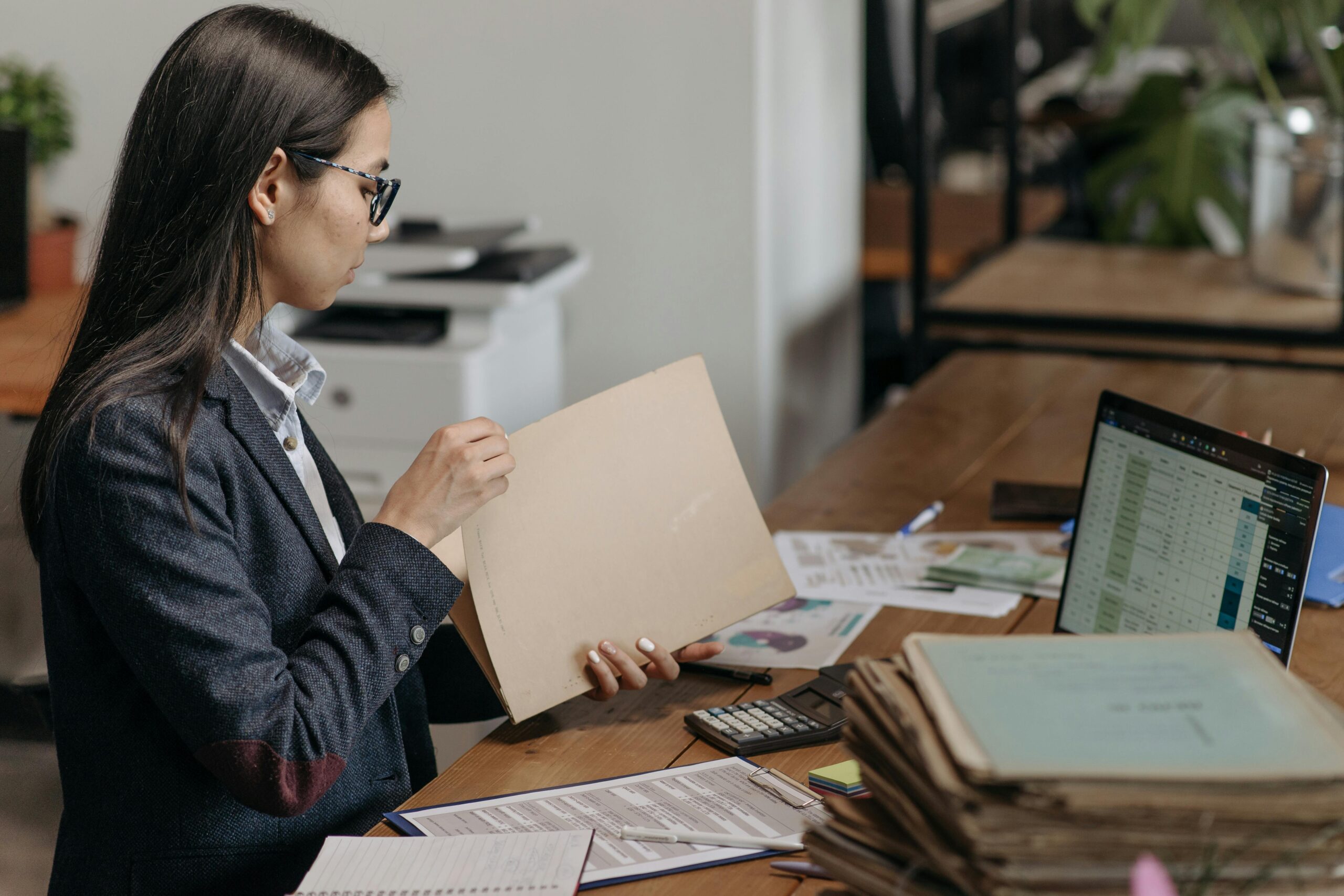 A professional woman reviews physical documents in a modern office—symbolizing the outdated manual processes that automation is helping tax firms move beyond.