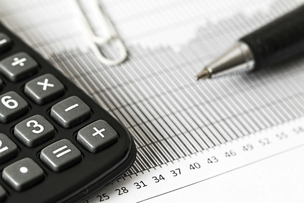 An image showing a calculator and pen on a table against tax forms.