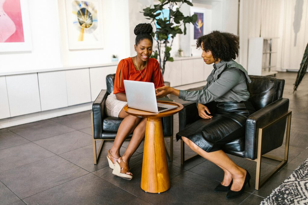 Two women sit together in a cozy, well-lit room, focused on a laptop—representing the collaborative decision-making and proactive strategy sessions high net worth individuals may need in light of the "One Big Beautiful Bill." As tax laws shift, informed discussions like these become crucial for navigating complex estate planning, trust structures, and generational wealth transfers.