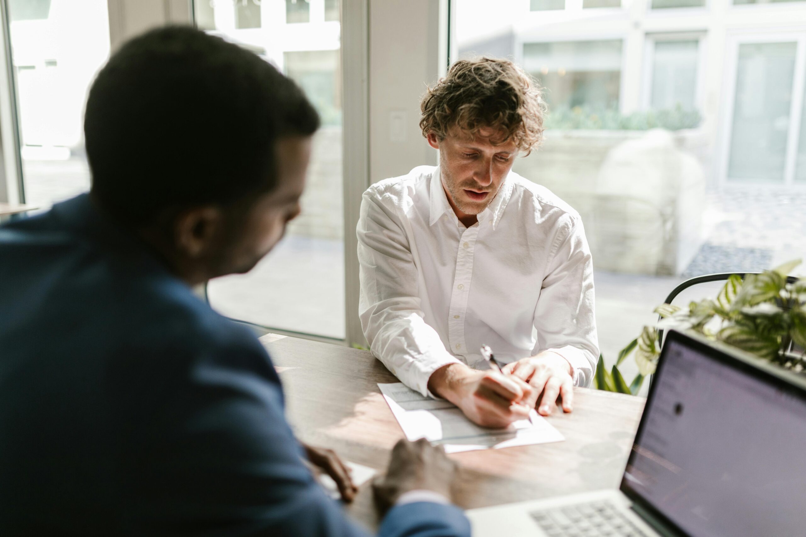 A business professional signs a document in an office setting—representing the traditionally manual and time-consuming engagement letter process in tax client onboarding.