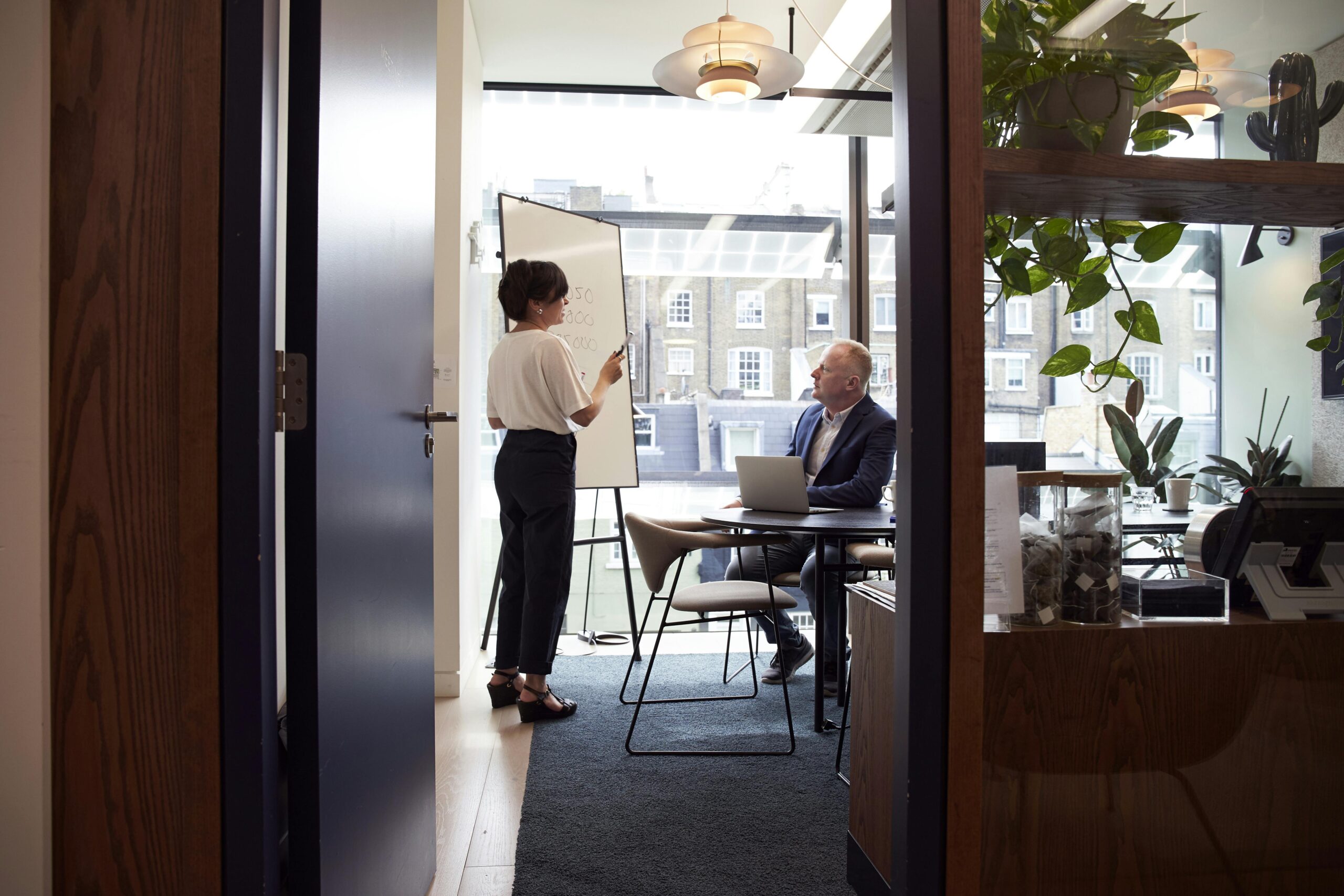 A professional woman gives a presentation in a modern office—symbolizing how real estate firms are reevaluating investment strategies in light of the One, Big, Beautiful Bill’s sweeping tax reforms.