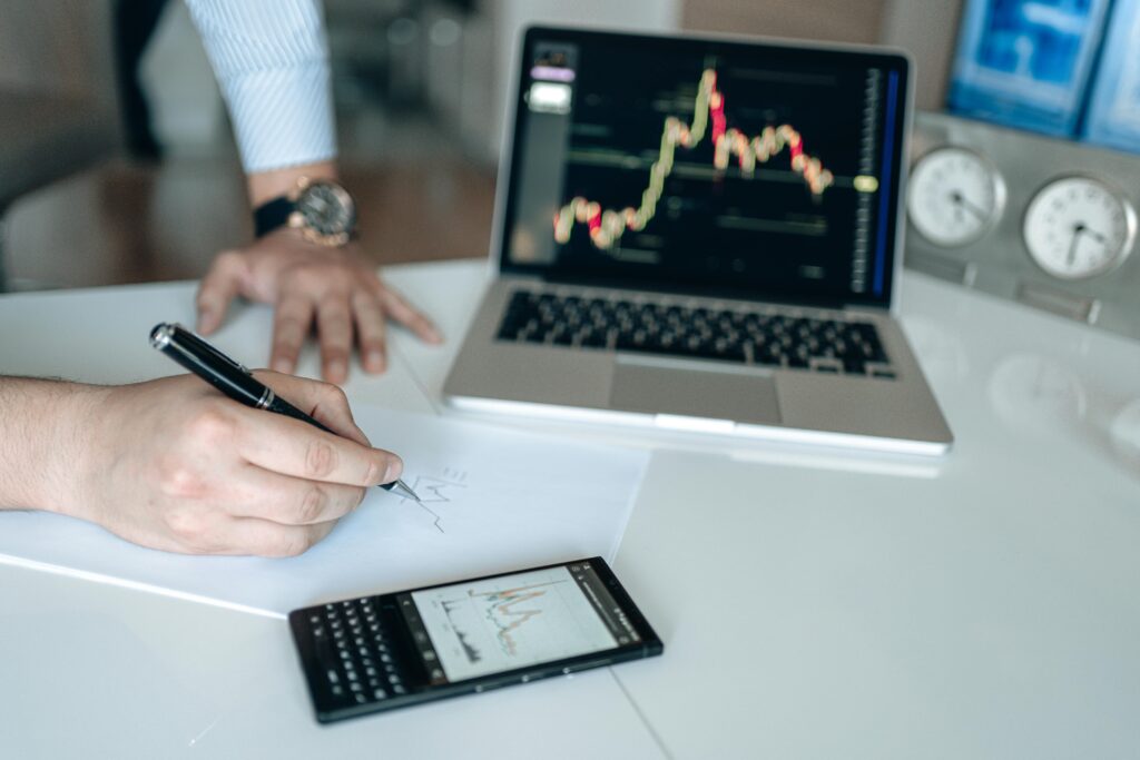A person drawing a financial chart on paper—symbolizing the importance of tracking crypto performance and holding periods to accurately distinguish between short-term and long-term gains.