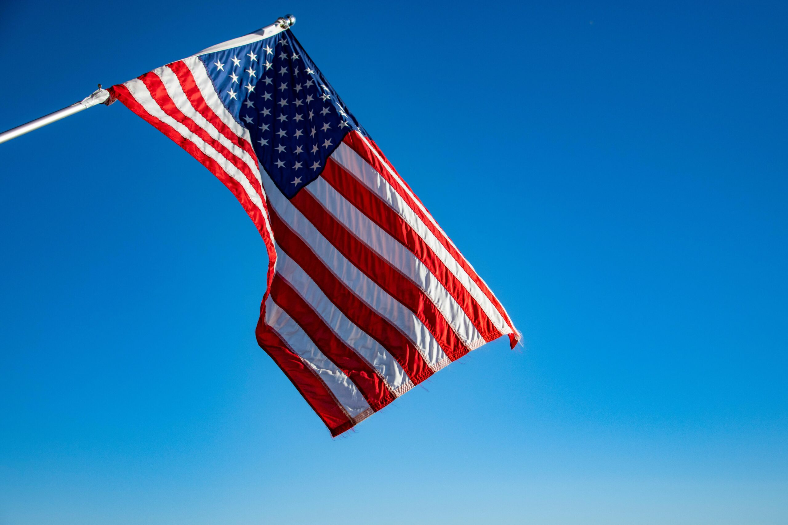 The American flag waving in the wind—symbolizing the continued U.S. tax obligations faced by American citizens living abroad, regardless of residence.
