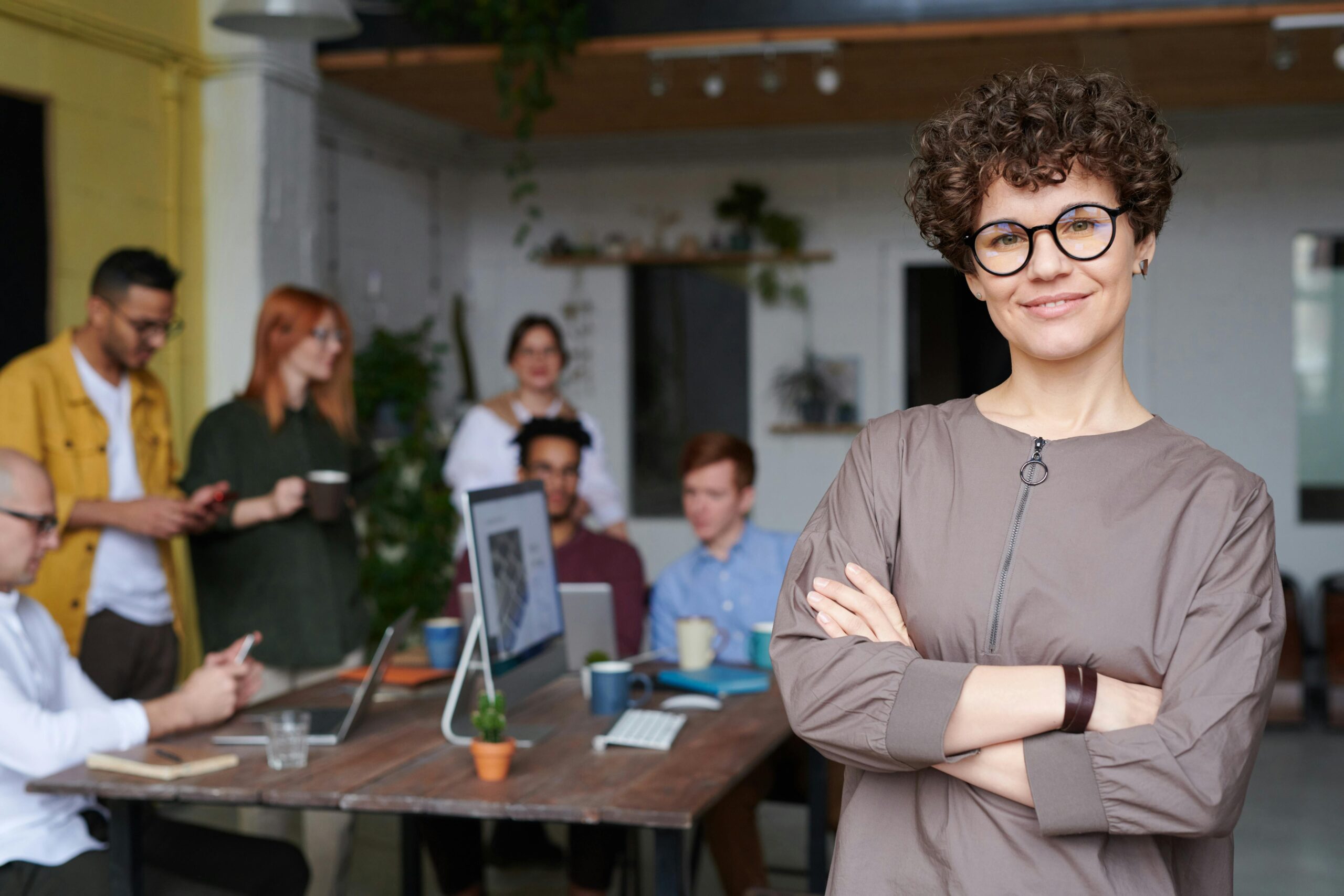 Entrepreneur standing aside from her team at work around a conference table. Business owners everywhere stand to gain big from Trump's signature legislation, "One, Big, Beautiful Bill" (OBBB).
