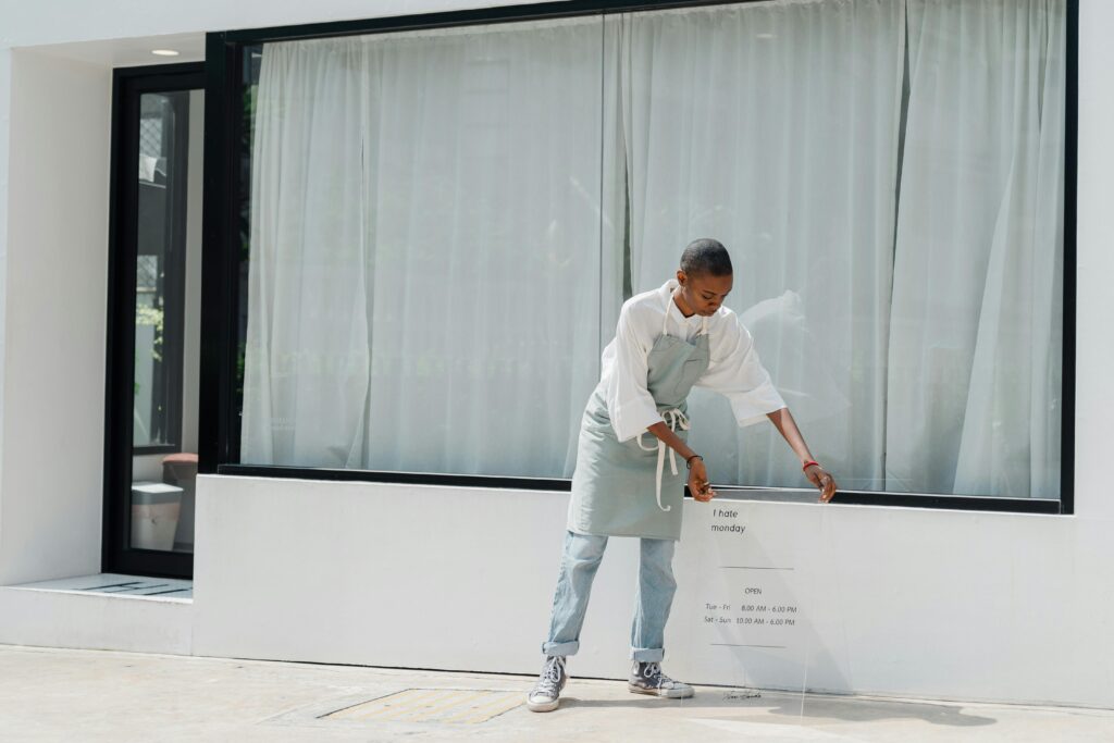 A diligent woman sets up a signboard outside her café on a sunny day—symbolizing the hands-on dedication of entrepreneurs navigating real-world challenges. As the "One Big Beautiful Bill" reshapes tax policy, small business owners must balance day-to-day operations with long-term planning to optimize for potential shifts in deductions, pass-through income treatment, and compliance requirements