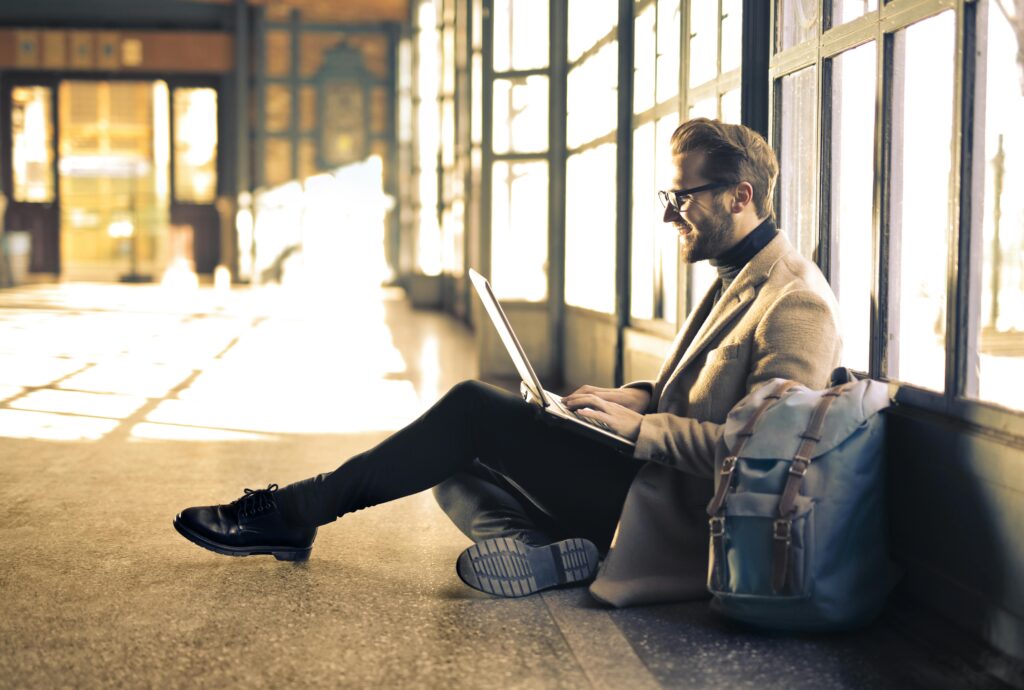 A man sitting on the ground in a hallway with his laptop to submit his e-file tax return.
