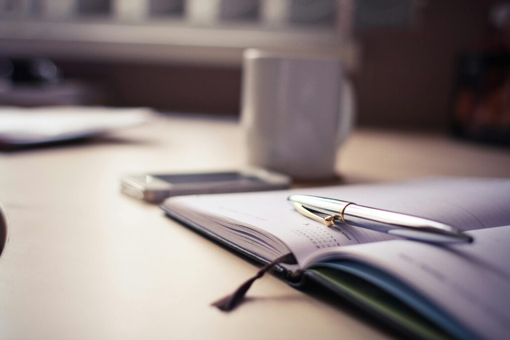 An open book with a silver pen placed on top—representing the importance of keeping detailed records and staying informed about evolving crypto tax regulations in 2025.