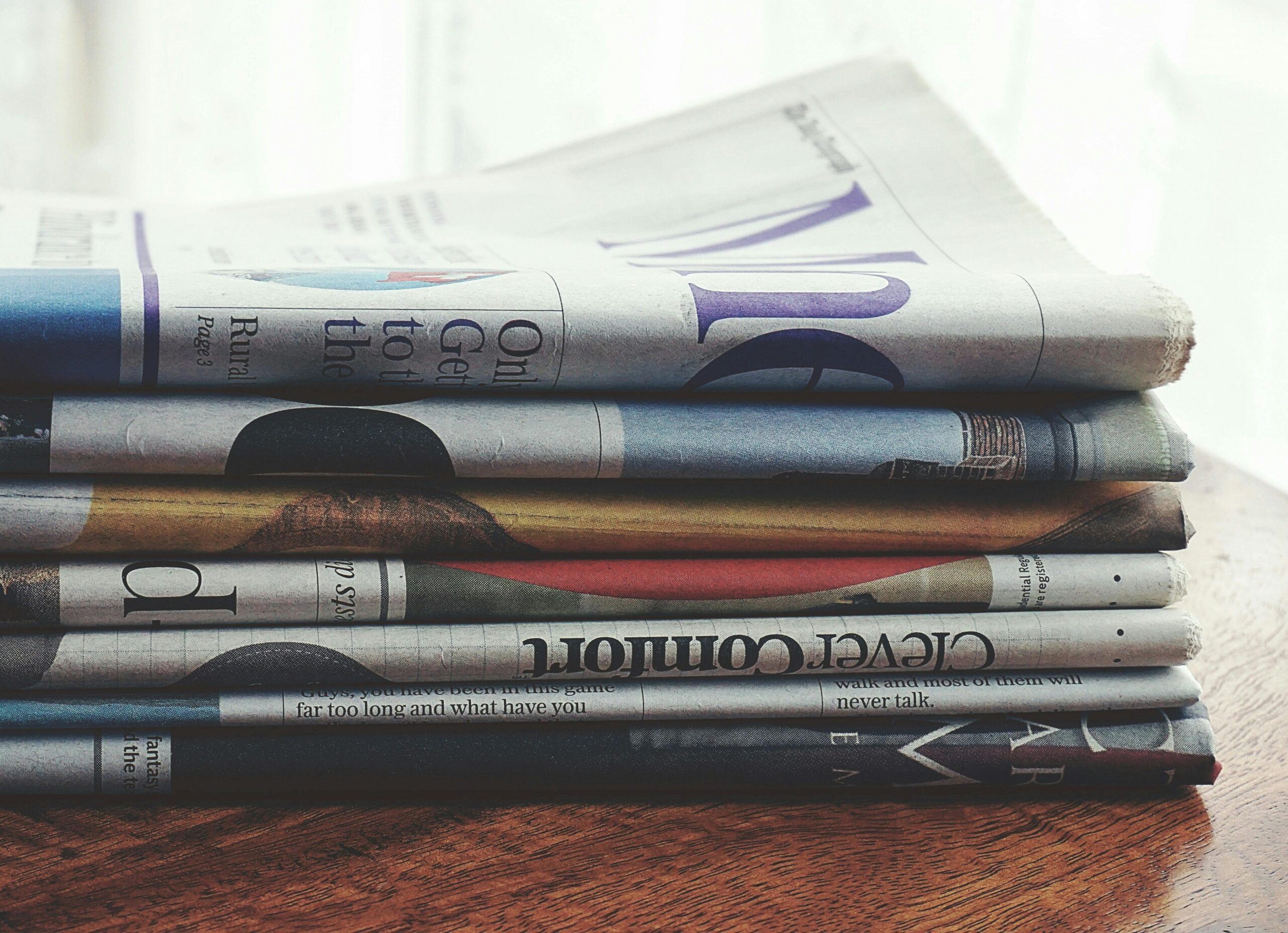 A stack of tax and finance magazines sits on a wooden surface, symbolizing the rapid flow of policy updates covered in the August 8, 2025 Tax Advisor Weekly. Topics include global tariff escalations, IRS enforcement priorities, and what’s ahead for retirement planning.