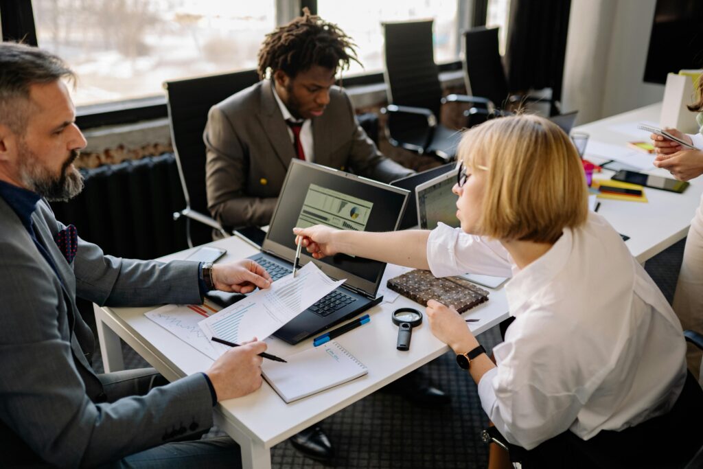 Three colleagues at an open work table discussing tax documents.