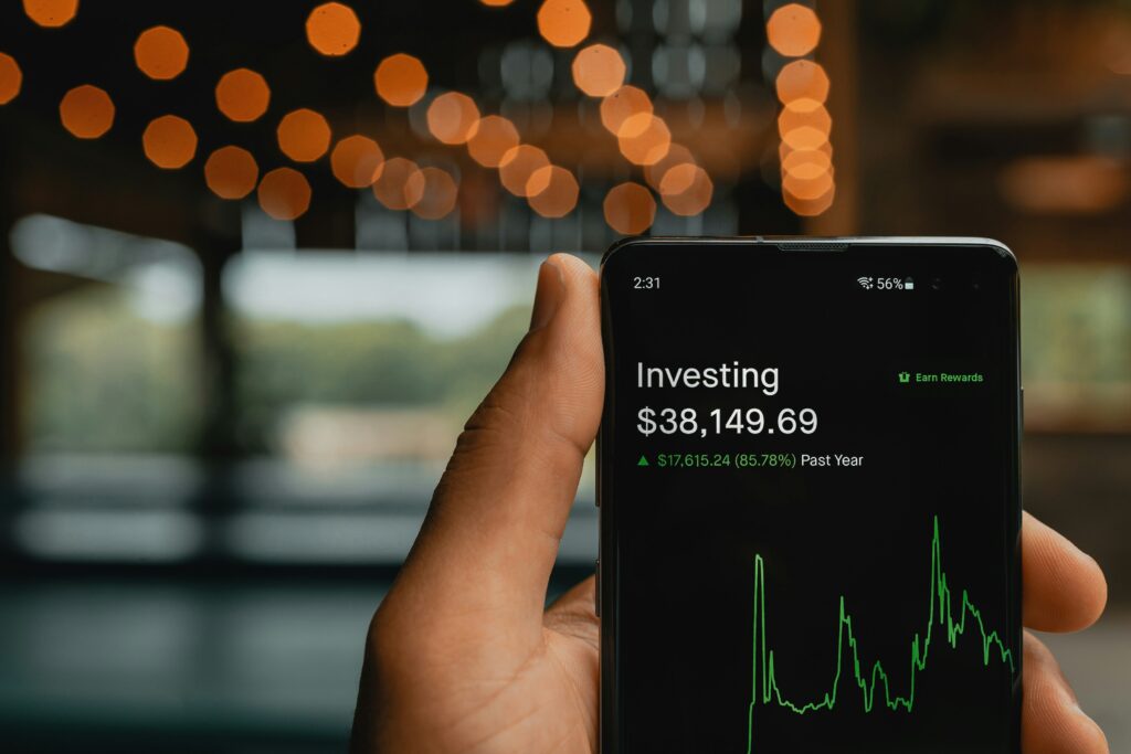 A close-up of a person holding a smartphone displaying an investing app, showing a portfolio balance of $38,149.69 with an 85.78% increase over the past year, represented by a green line graph—symbolizing how ESG-focused investments can potentially deliver strong returns while also offering tax benefits through strategic planning.