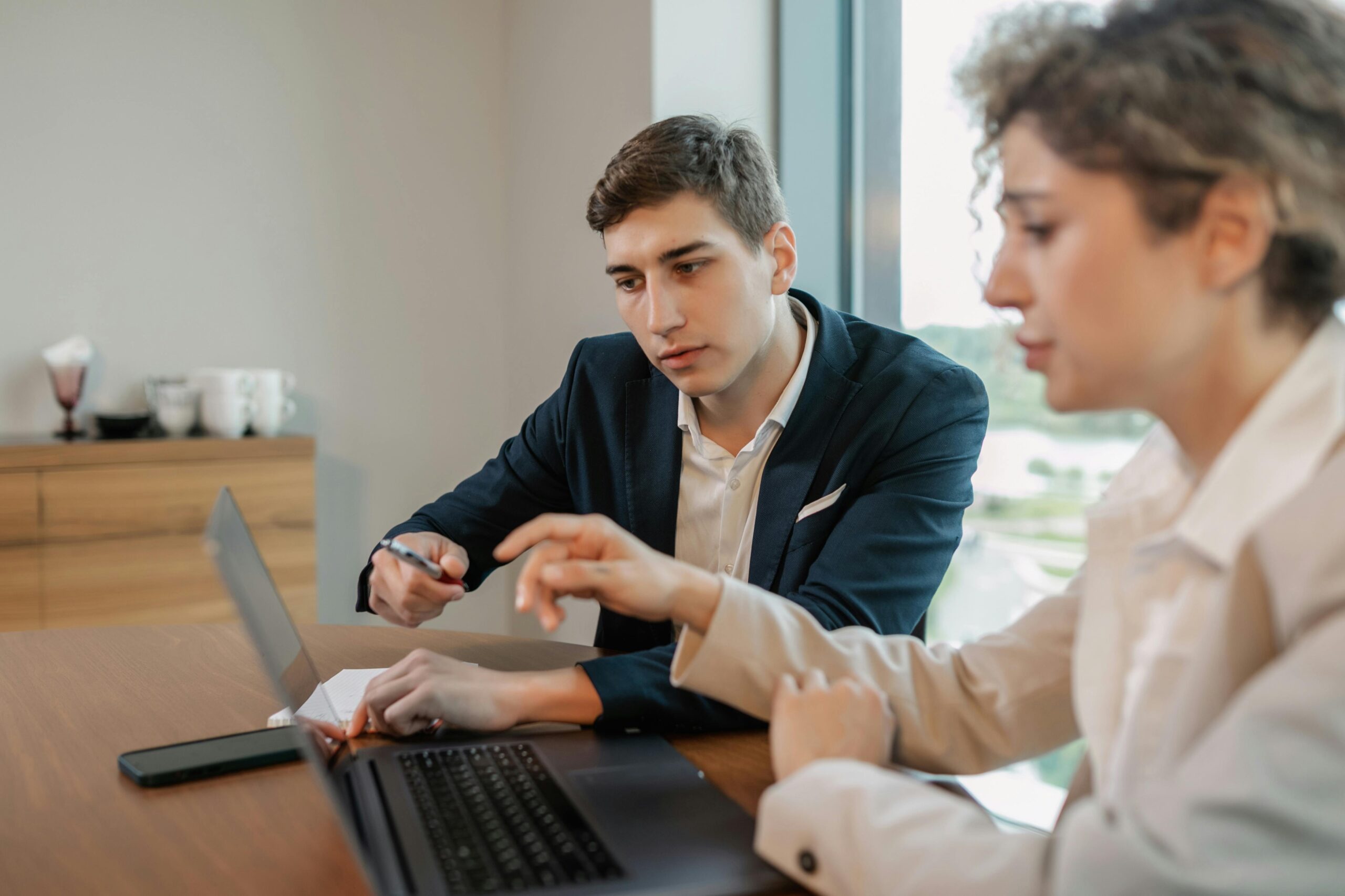 A man and woman sitting at a table with a laptop, smiling as they review documents—representing small business owners tackling S Corp tax filings with confidence.