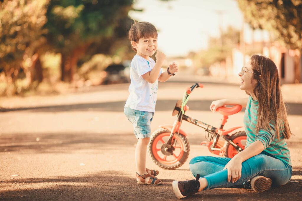 Image of a woman sitting on the floor with her son smiling.