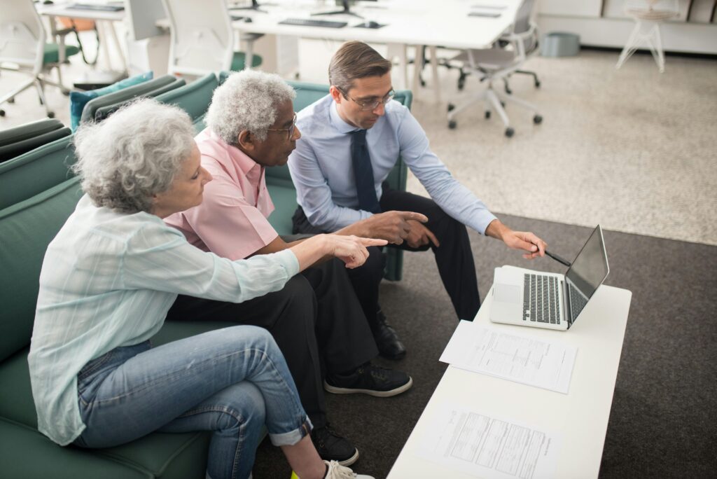 A group of people sitting comfortably on a couch, focused on a laptop screen—symbolizing a family or legal team exploring tax-efficient estate planning tools like IDGTs.