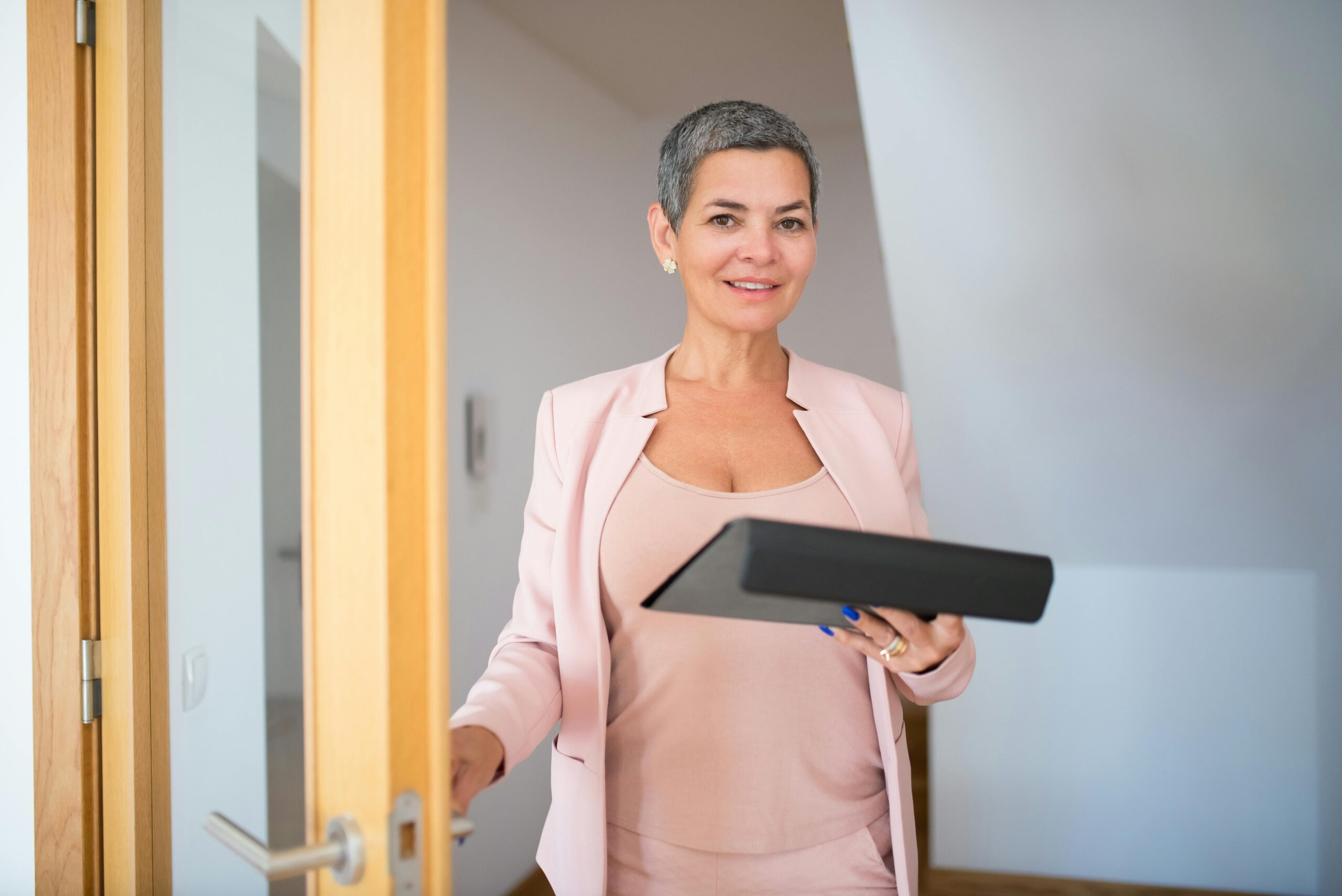 A confident woman holding a tablet while seated at a desk—representing a high net worth retiree reviewing strategies to minimize required minimum distribution (RMD) taxes and optimize retirement income planning.