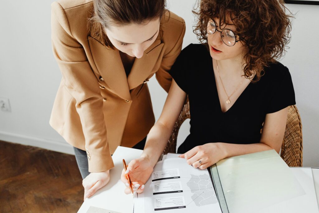 Two women collaborate over financial paperwork—illustrating the role of tax professionals using smart tools and strategic planning to help clients reduce their NIIT liability and improve after-tax outcomes.