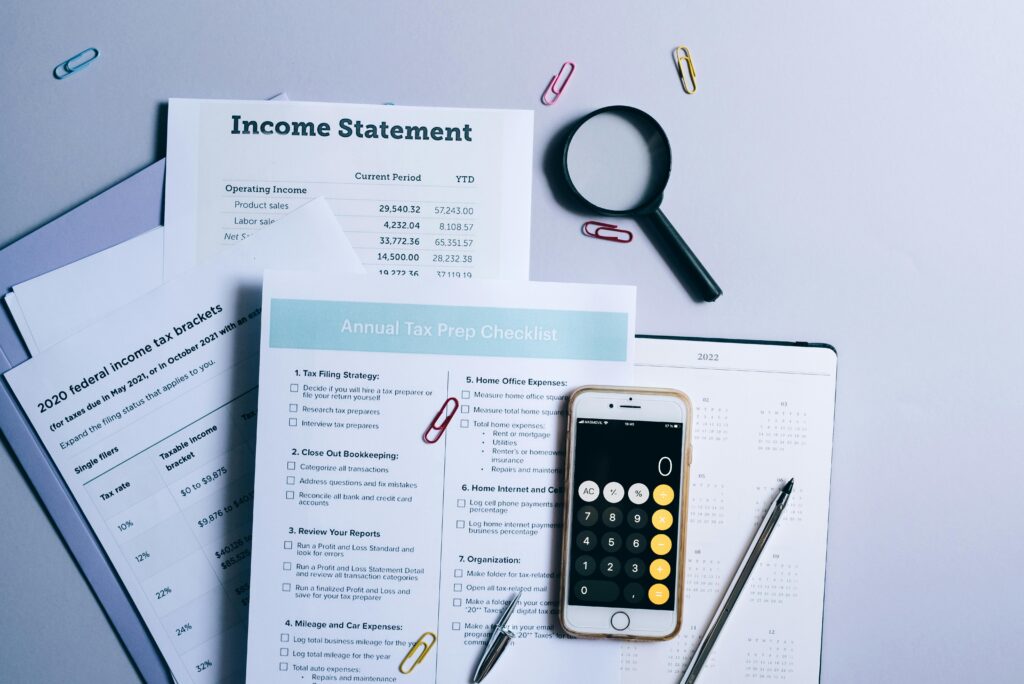 Image of paperwork on a table with a calculator on top.