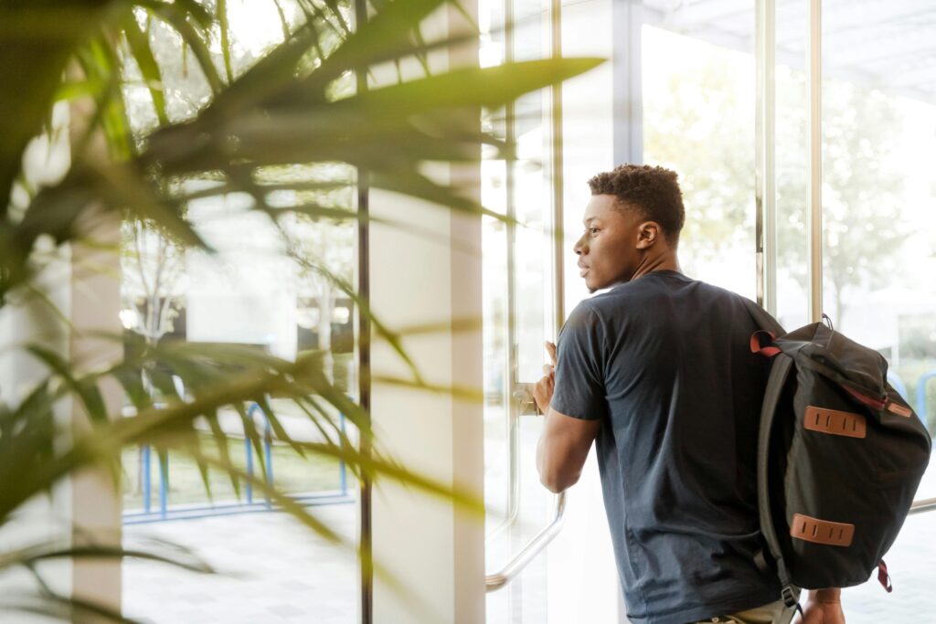 A man with a backpack looks out a window, evoking a sense of reflection and planning—symbolic of individuals reevaluating their retirement and inheritance strategies in response to changes brought by the SECURE Act 2.0.