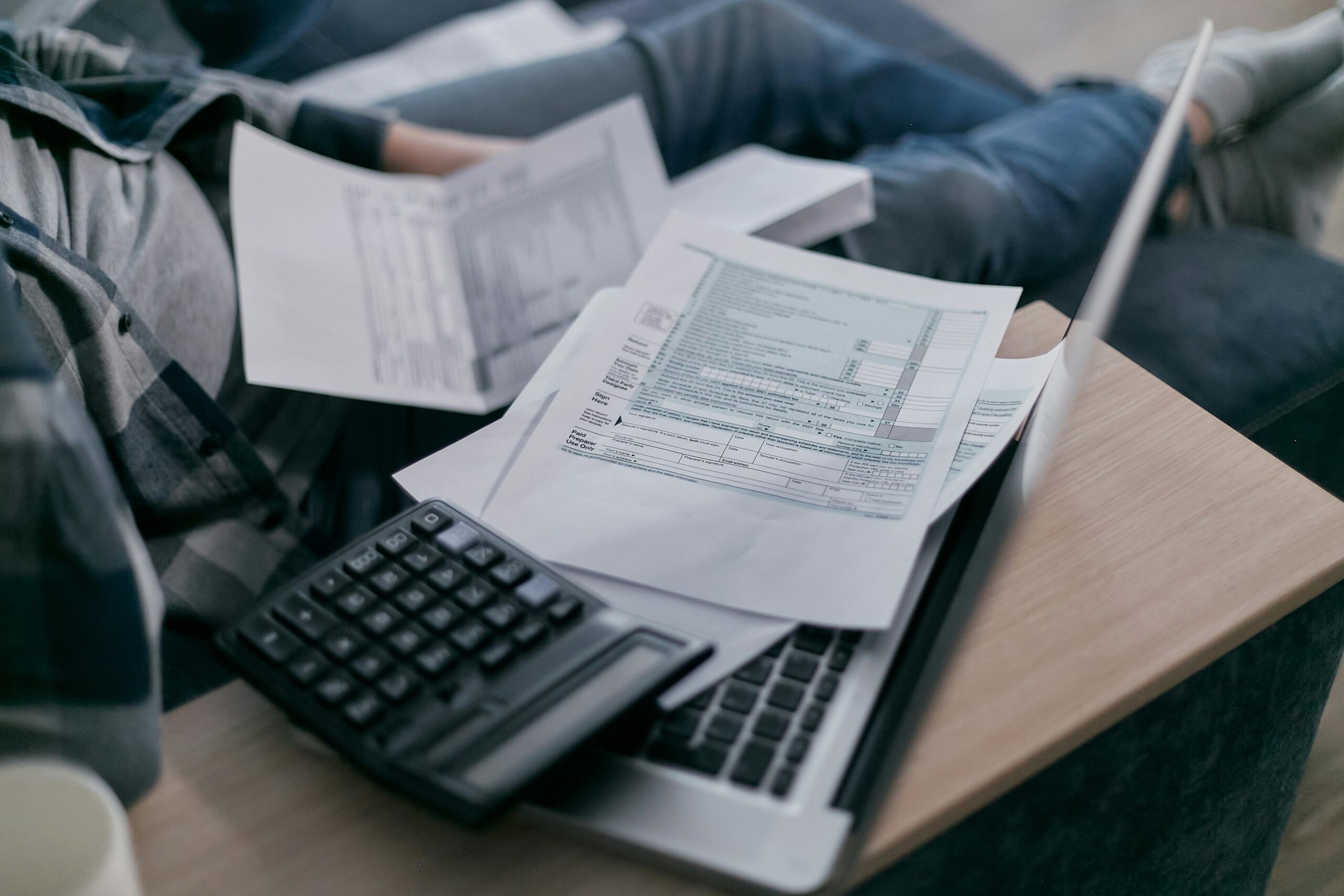 Flat lay of tax documents including W‑2 and W‑4 forms, with a calculator and pen—highlighting upcoming tax form complexity under 2026 payroll changes.