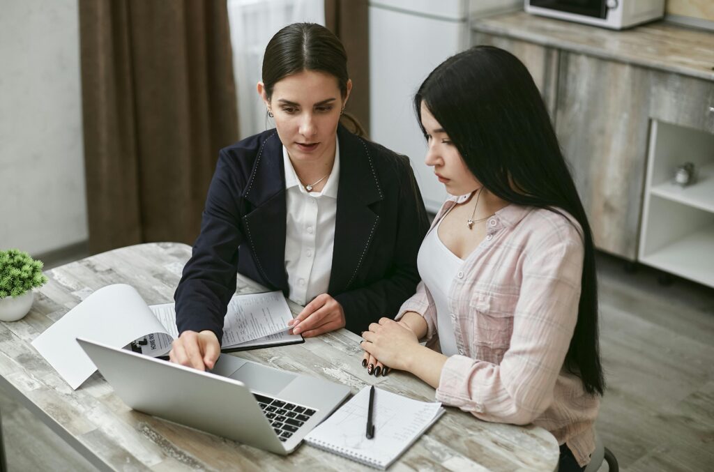 Two women looking at a laptop screen together—symbolizing entrepreneurs or partners walking through Form 1120-S instructions step by step.