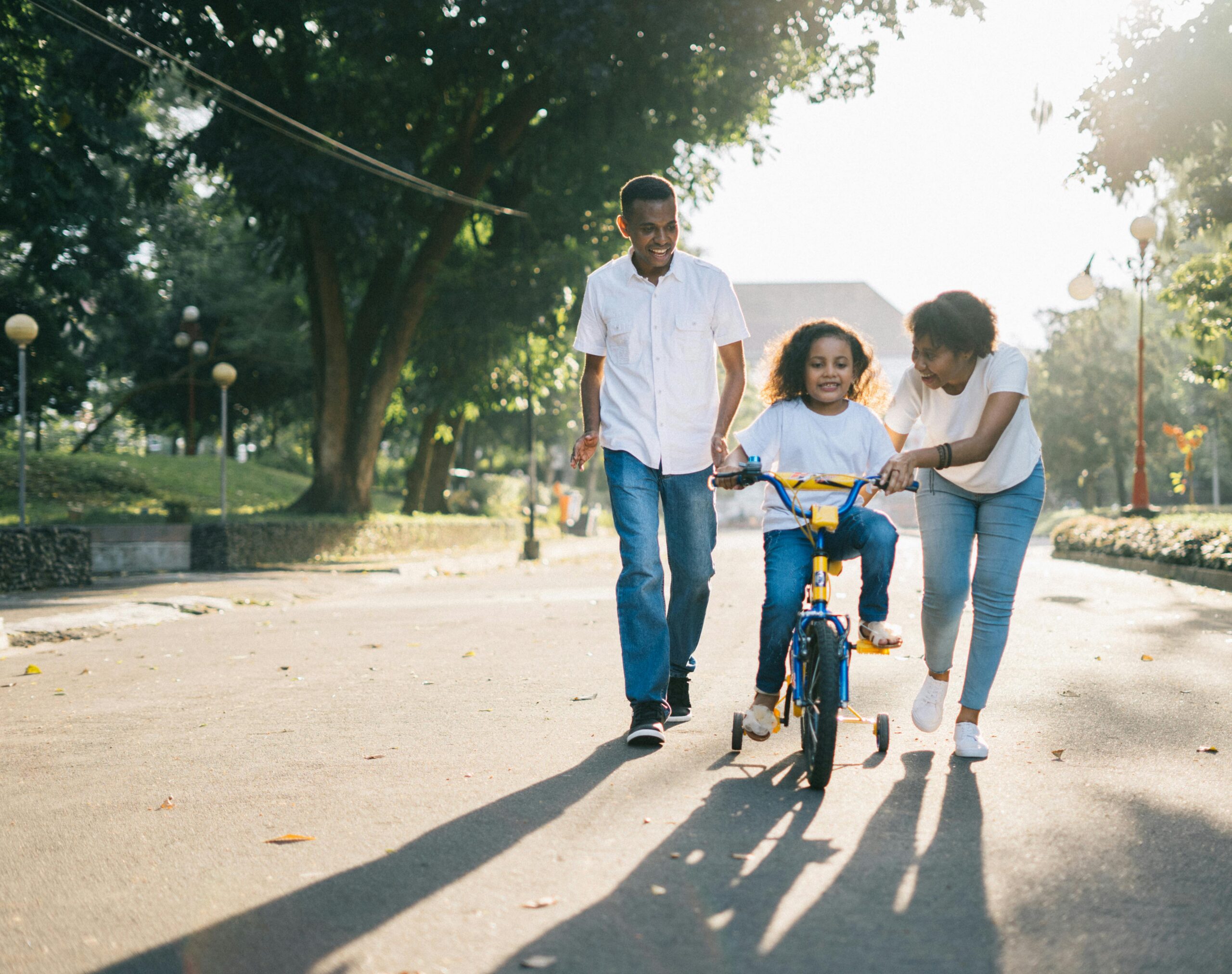 Image of a family on the street with their child cycling with them.