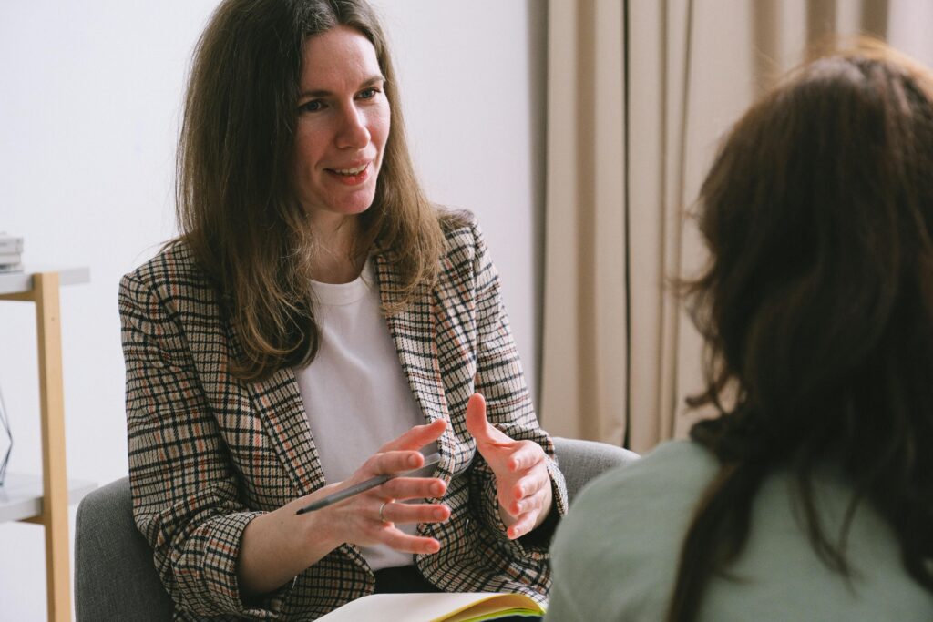 A smiling woman holding a notebook while speaking with another person—evoking the approachable, consultative nature of discussing IDGTs with a financial advisor or estate planner.