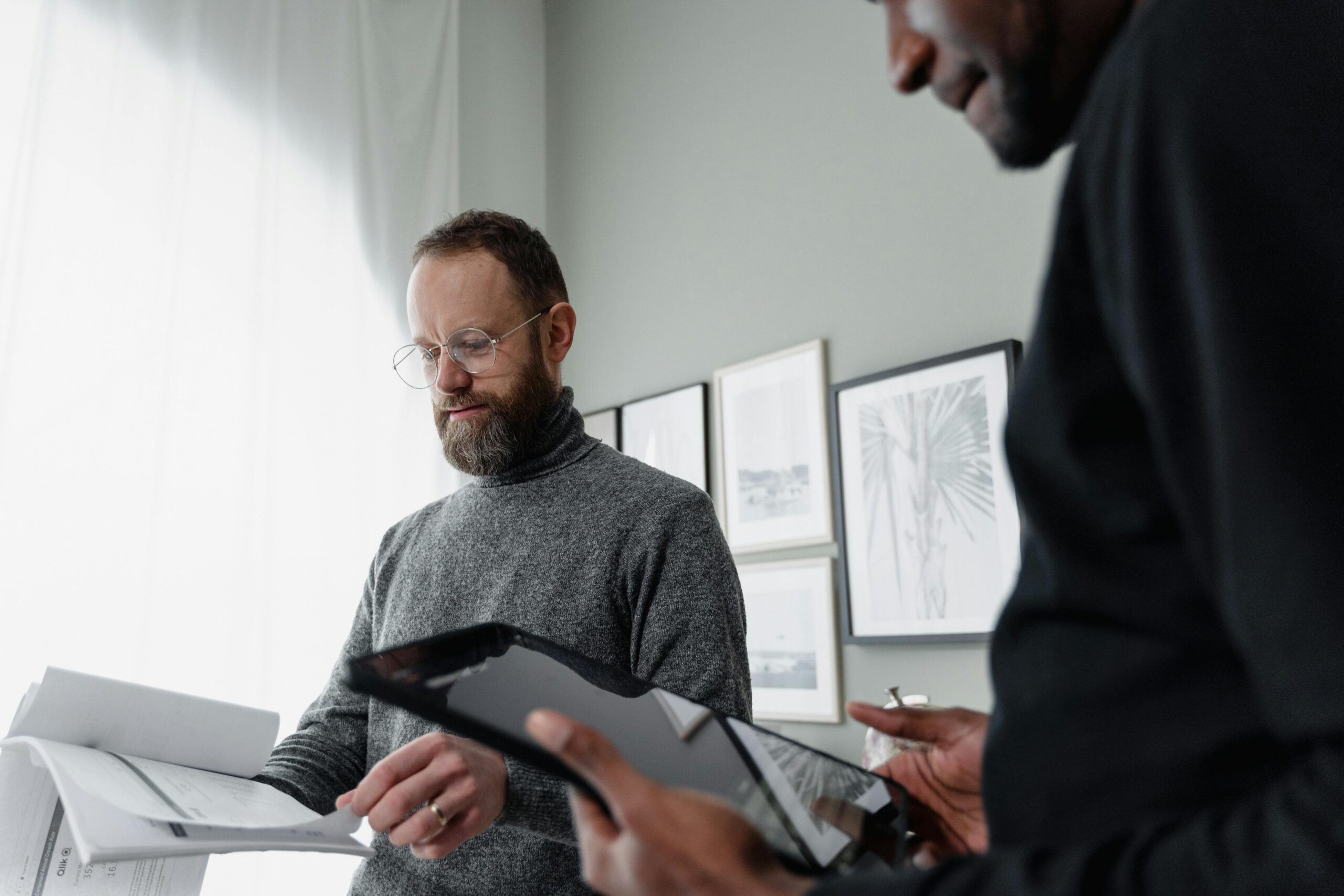 Two business partners reviewing financial documents and digital reports—symbolizing the critical due diligence required when structuring buy-sell agreements to avoid costly tax traps.