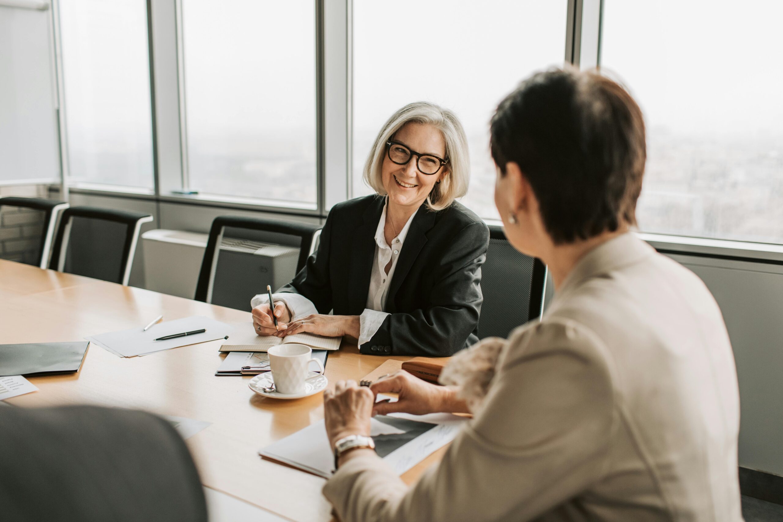 A professional woman in a modern office setting attentively listens during a discussion—symbolizing the importance of expert tax guidance when navigating inheritance strategies like the Step-Up in Basis.