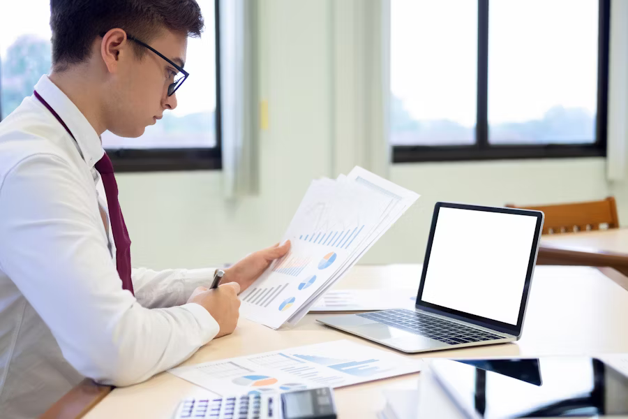 A professional reviewing marketing and investment data at a desk—representing how contribution margin calculations inform smarter pricing, tax planning, and operational decisions.