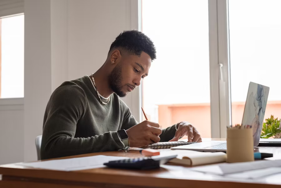 A man reviewing tax documents on a laptop at his desk—symbolizing the final review process of W-2 information, including Box 12, before submitting a return.