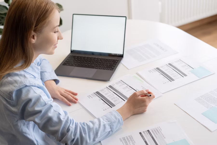Overhead view of a businesswoman analyzing financial documents at a home office—illustrating how entrepreneurs can use contribution margin insights to evaluate profit drivers and control costs.
