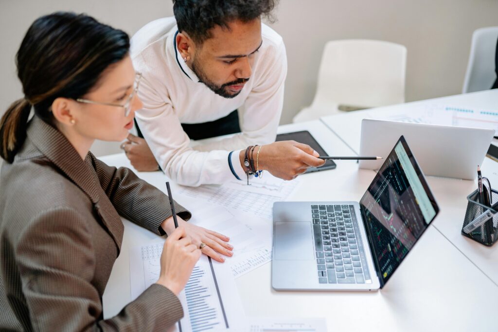 Professional tax advisors collaborating over a laptop in an office setting.