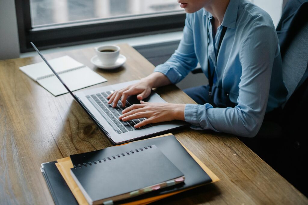 Person calculating estimated taxes on a MacBook Pro at a wooden table.